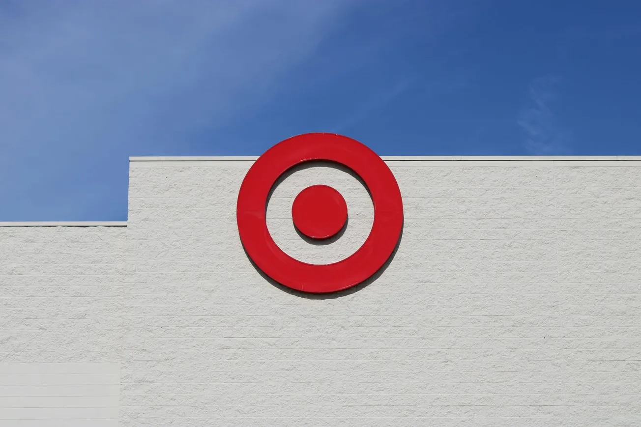 Target bullseye logo on a white building against a clear blue sky. The minimalistic design conveys a sense of modernity and simplicity.