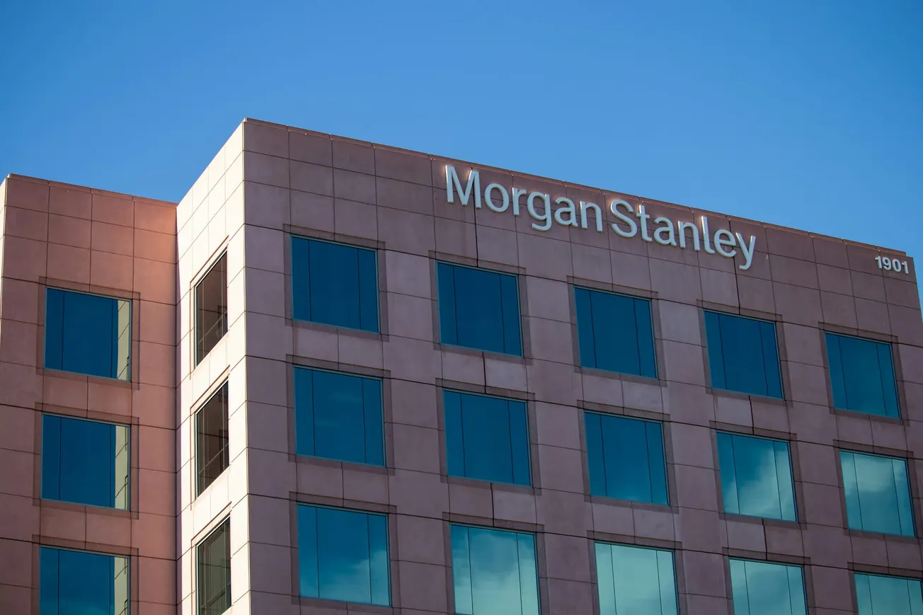 A brown office building with the name "Morgan Stanley" at the top, reflecting a clear blue sky in its windows, suggesting corporate professionalism.