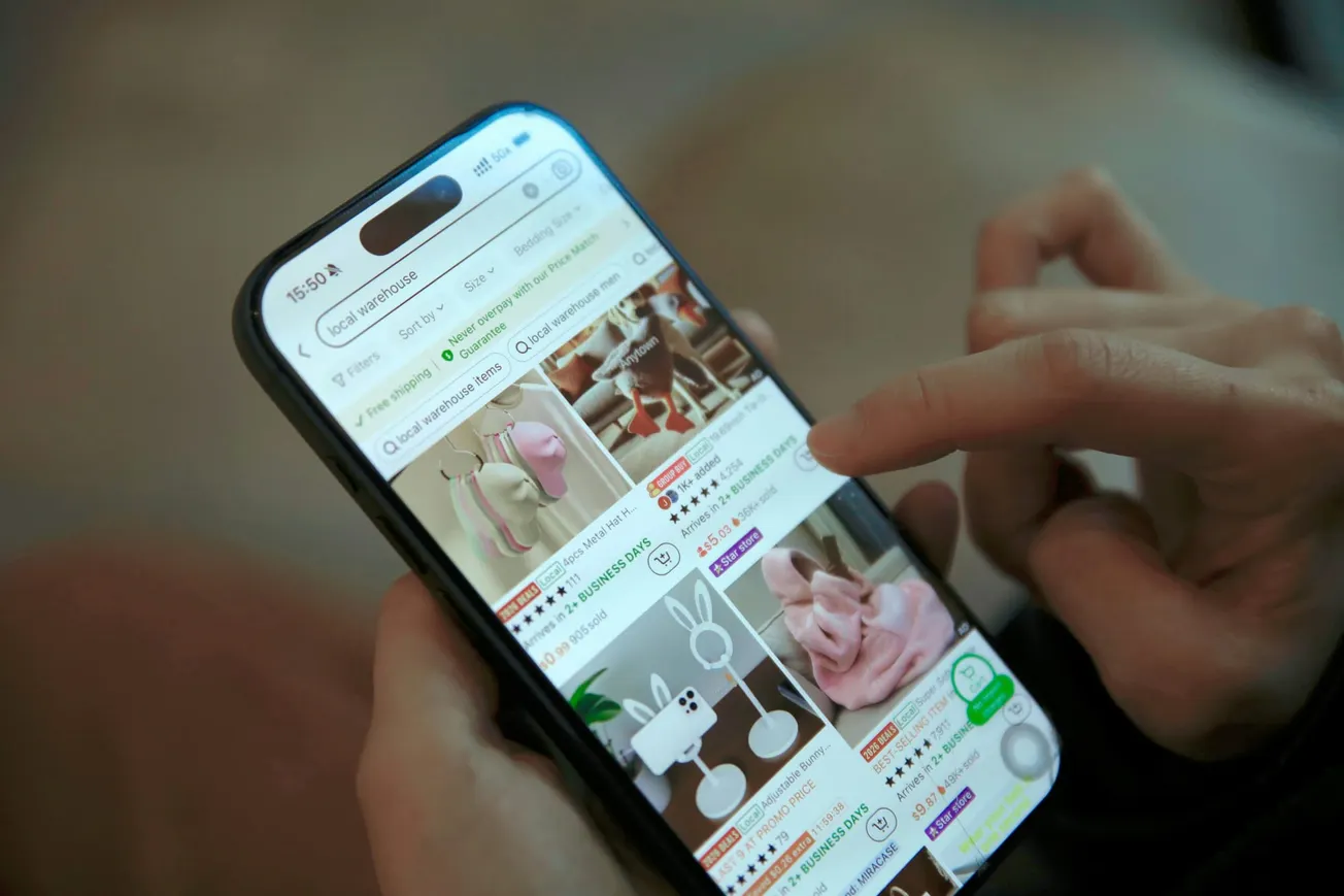 A person uses a smartphone to browse an online shopping app displaying home decor items. The screen shows various decorative objects.