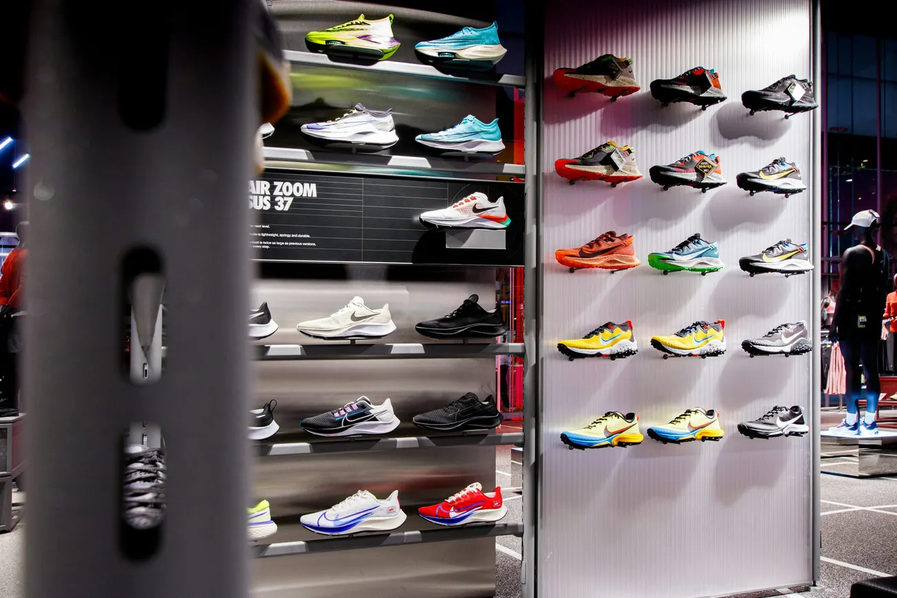 Display of colorful athletic shoes on two wall-mounted racks in a modern store. Vibrant hues and sleek designs create an energetic and stylish atmosphere.