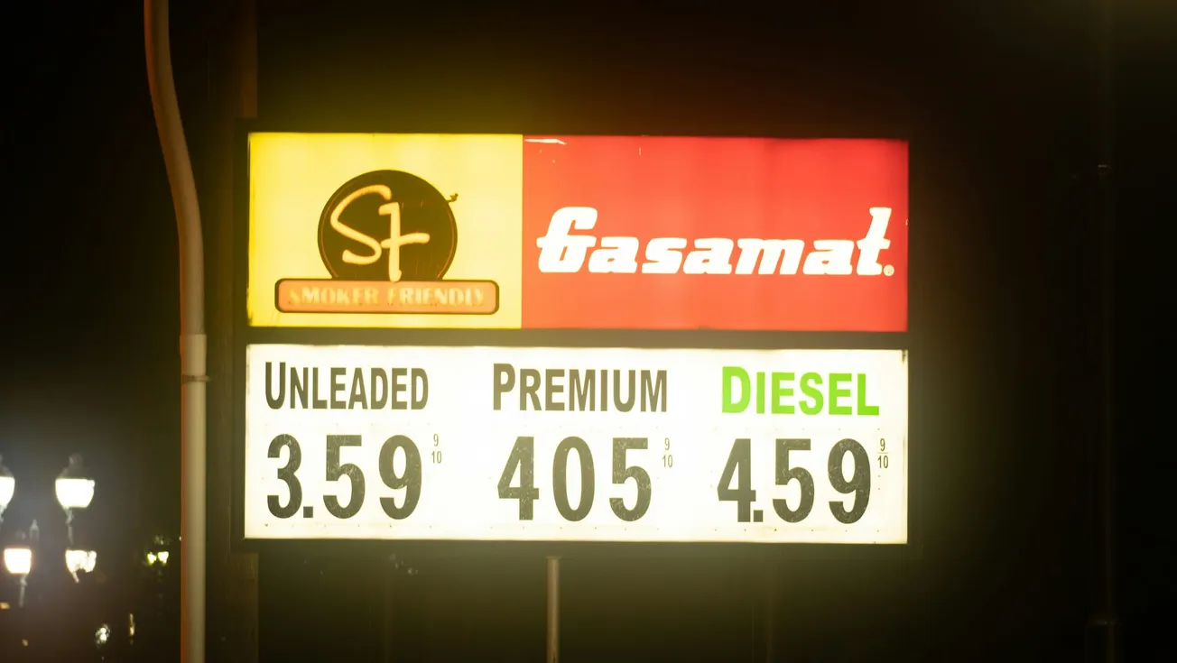 Gas station sign at night displaying fuel prices: Unleaded $3.59, Premium $4.05, Diesel $4.59. "Smoker Friendly" and "Gasamat" logos on top.