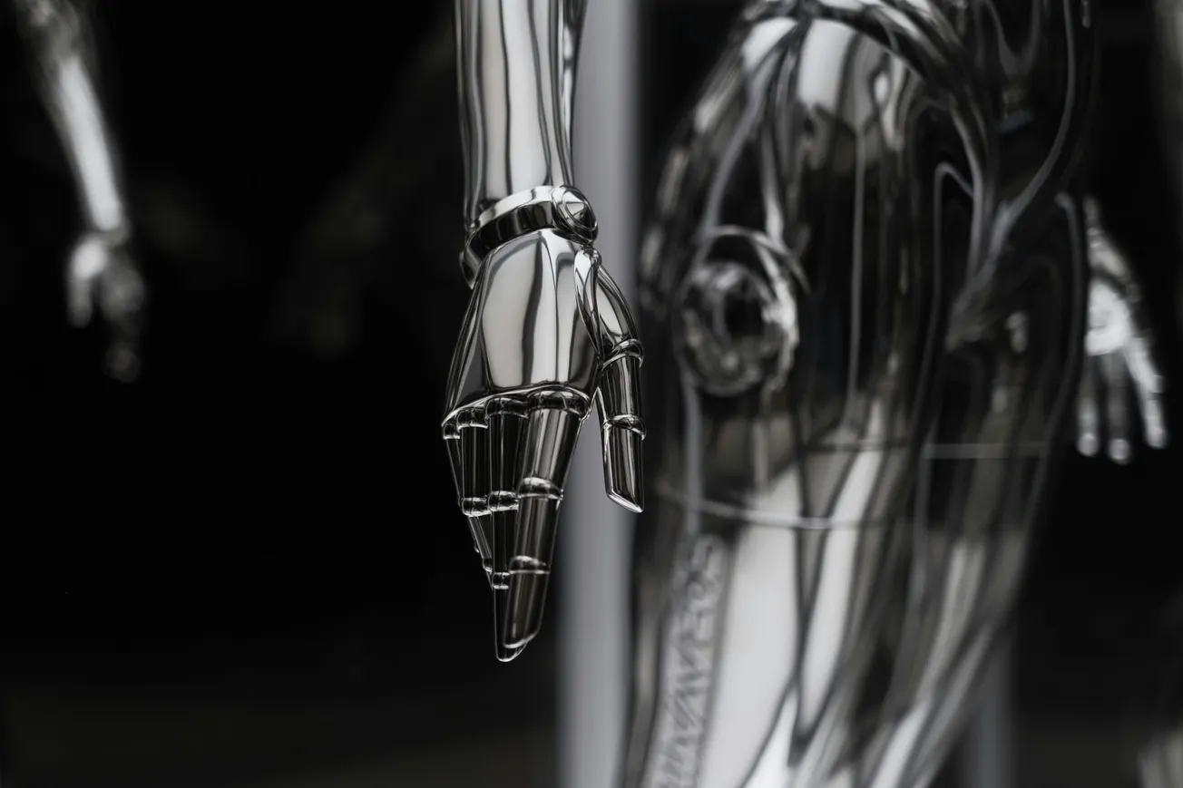 Close-up of a shiny, metallic robotic hand with articulated fingers, set against a dark background. The polished surface reflects light, conveying a futuristic feel.