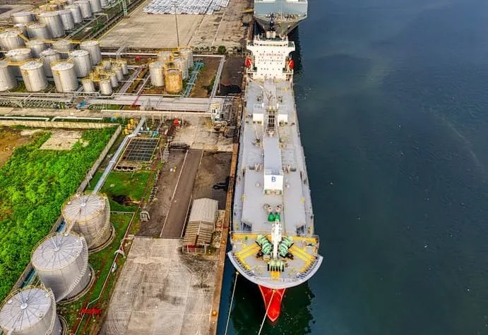 Massive oil tankers navigate busy shipping lanes and crude oil storage tanks, symbolizing the dynamic global energy trade and recent shifts in U.S. oil exports.