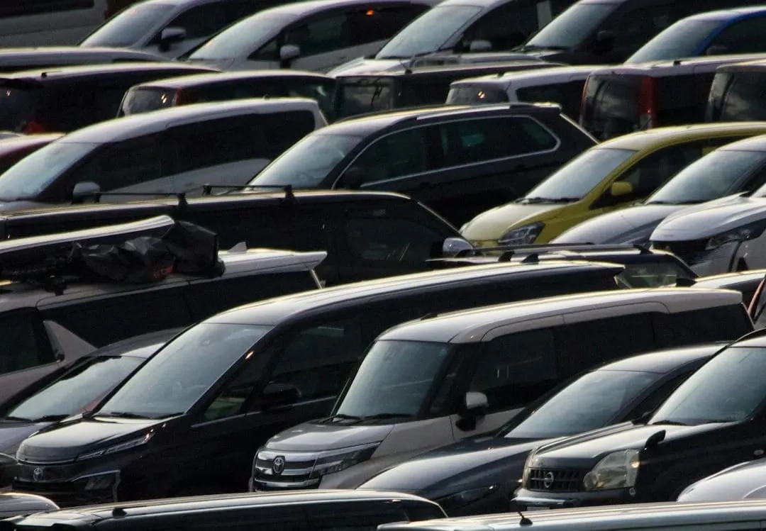 A discerning consumer evaluates an older vehicle on a dealership lot, highlighting shifts in automotive demand and current market dynamics.
