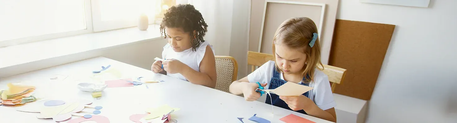 Children cutting paper engaged in Parallel Play