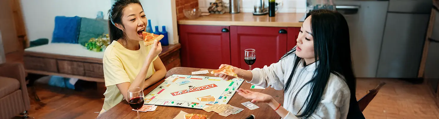 Two women socializing while playing Monopoly