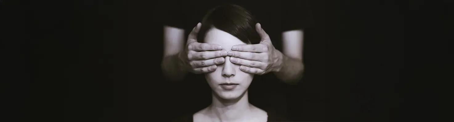 Black-and-white photo of hands covering eyes, symbolizing the ‘Out of Sight, Out of Mind’ ADHD savings method to curb impulse spending.