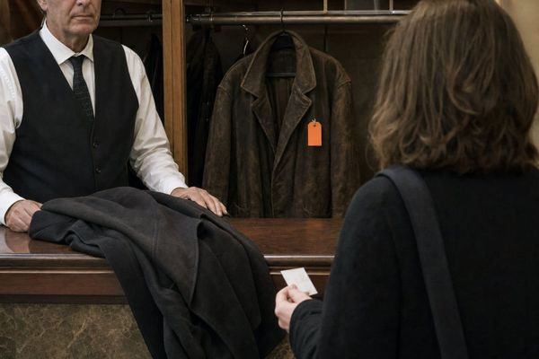 A coat-check attendant pauses over a new coat while the claim tag remains on the old one: the handover stops because the replacement has no recorded link.