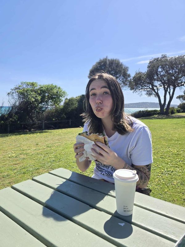 Phoebe eating a $25 panini at the beach