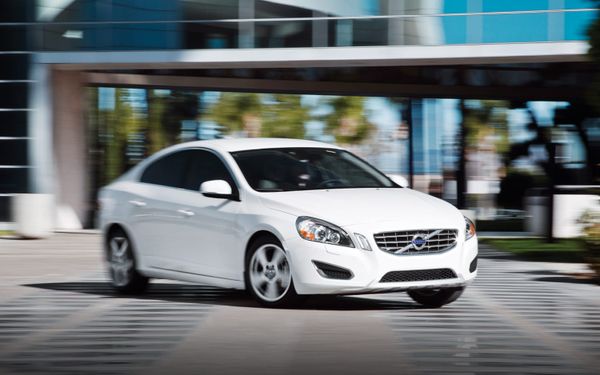 A white Volvo car in motion.