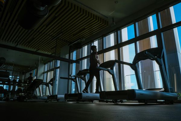 Photo of a man running on a treadmill in a dim room.