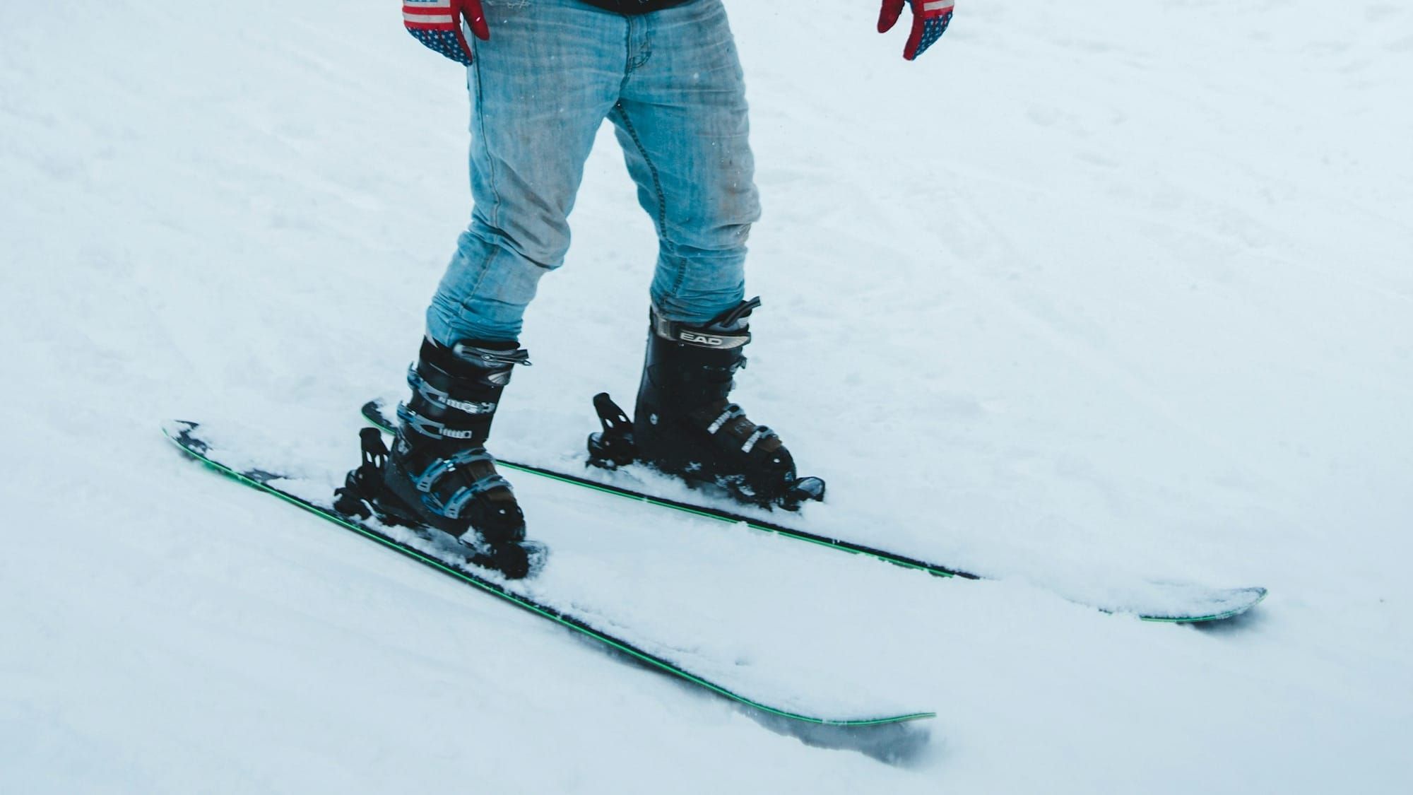 Man wears faded blue jeans while skiing on snow.