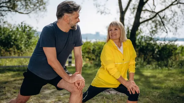 Couple exercisng with lunge stretches utdoors
