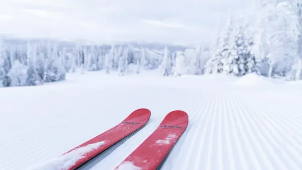 Red skis glide on a freshly groomed coderouy snow surface