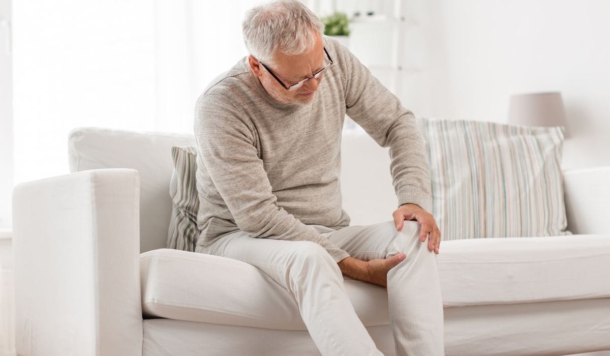 Gentleman at home on sofa with knee pain.