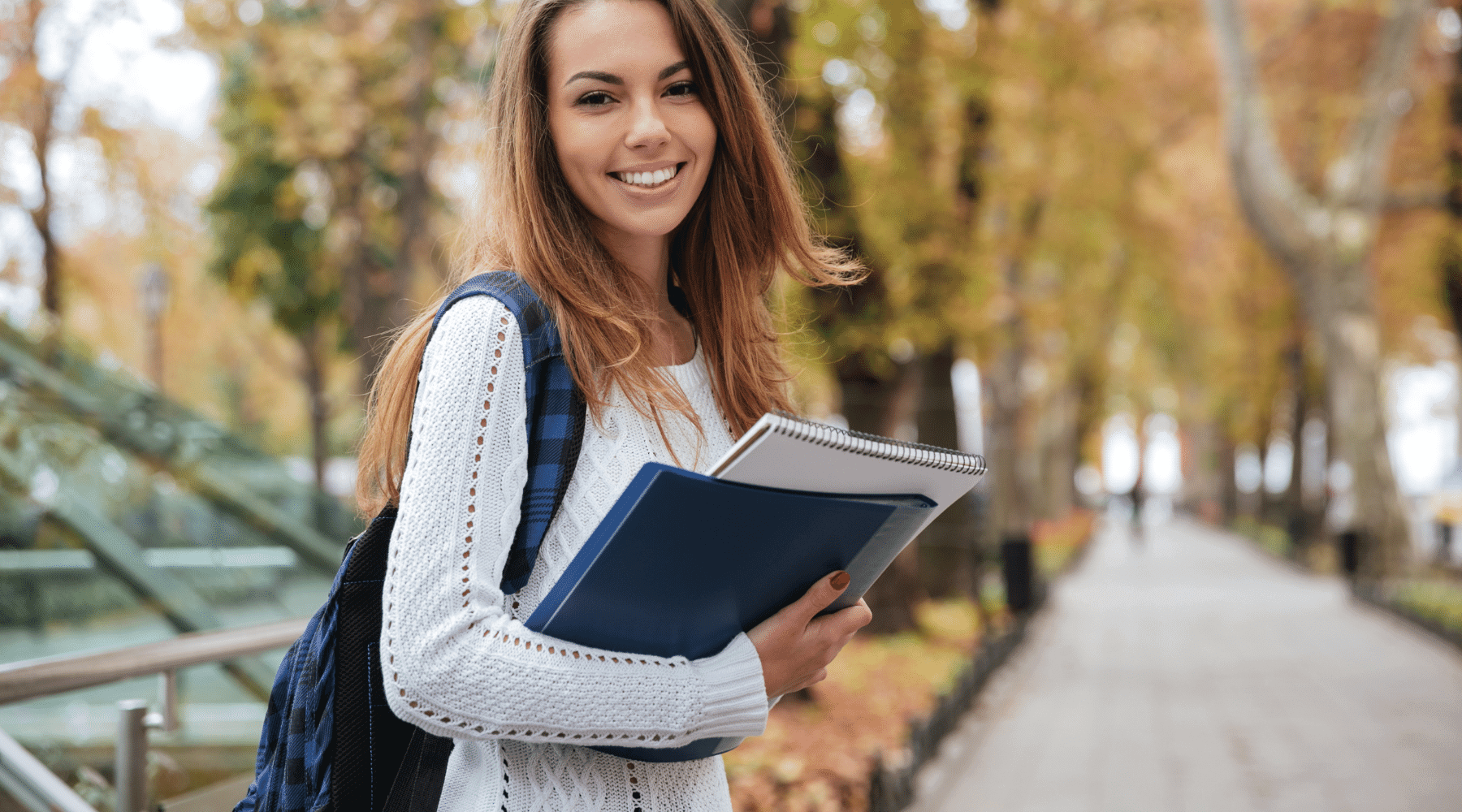 Young Teacher smiling with her backpack as she heads to class on campus.