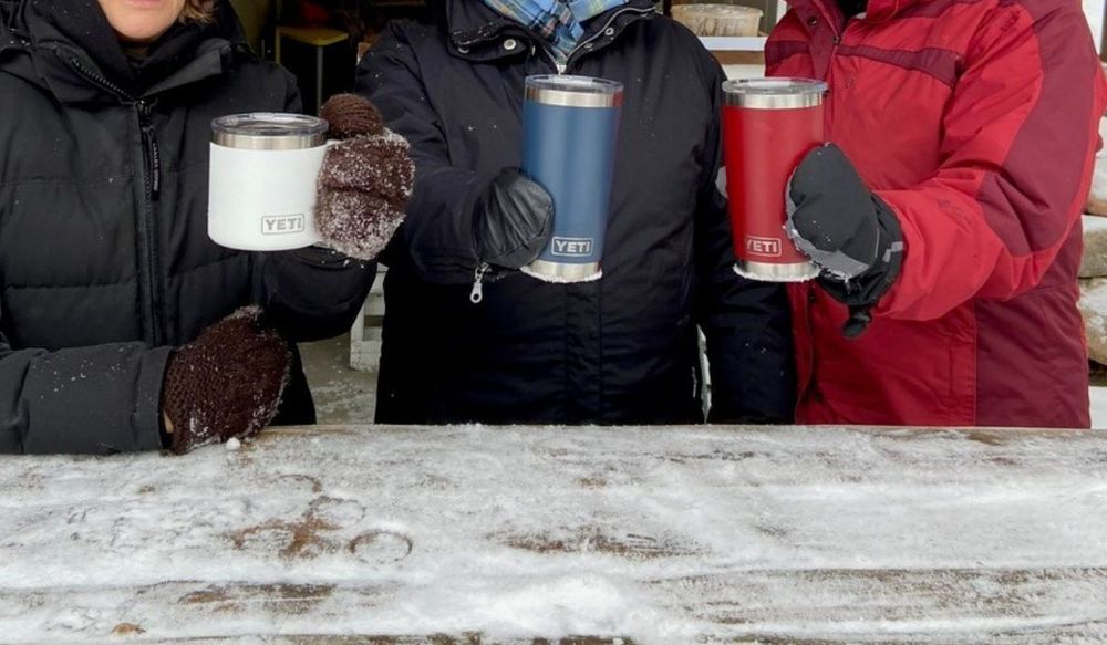 Friends enjoying hot drinks outside in the winter with Yeti Rambler Mug and Tumblers