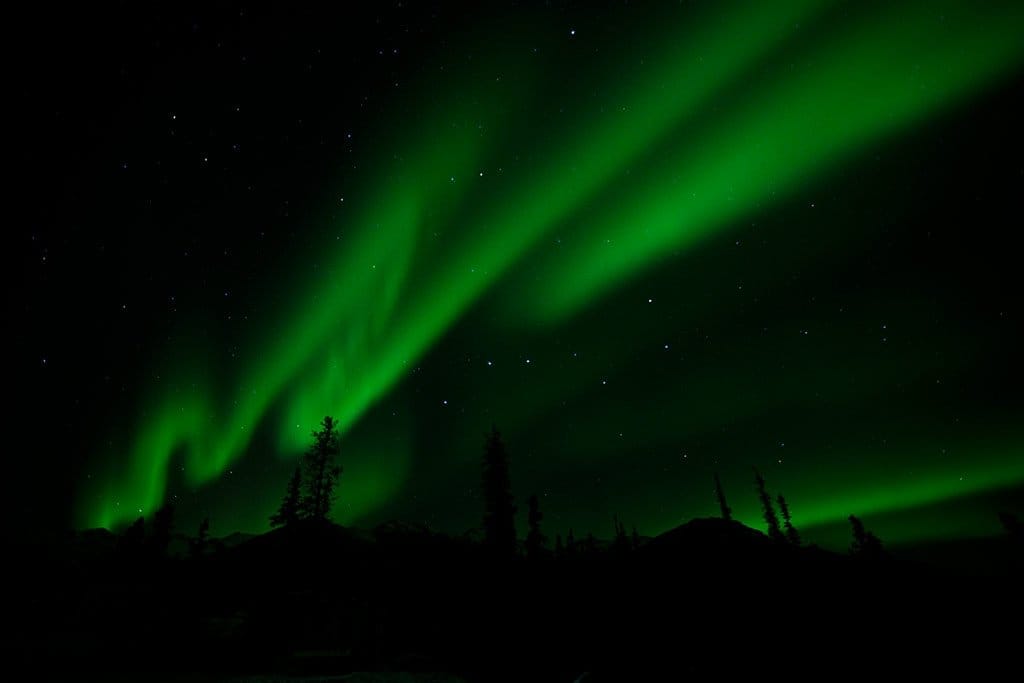 Green aurora borealis ribbons caused by charged particles striking oxygen, over Denali, Alaska