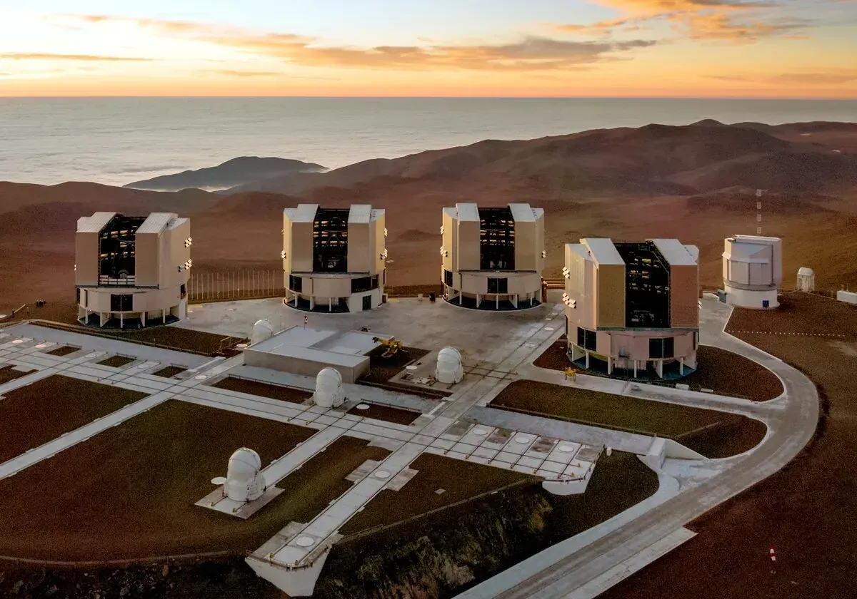 Professional telescopes of the Very Large Telescope at Paranal Observatory in Chile, silhouetted at sunset