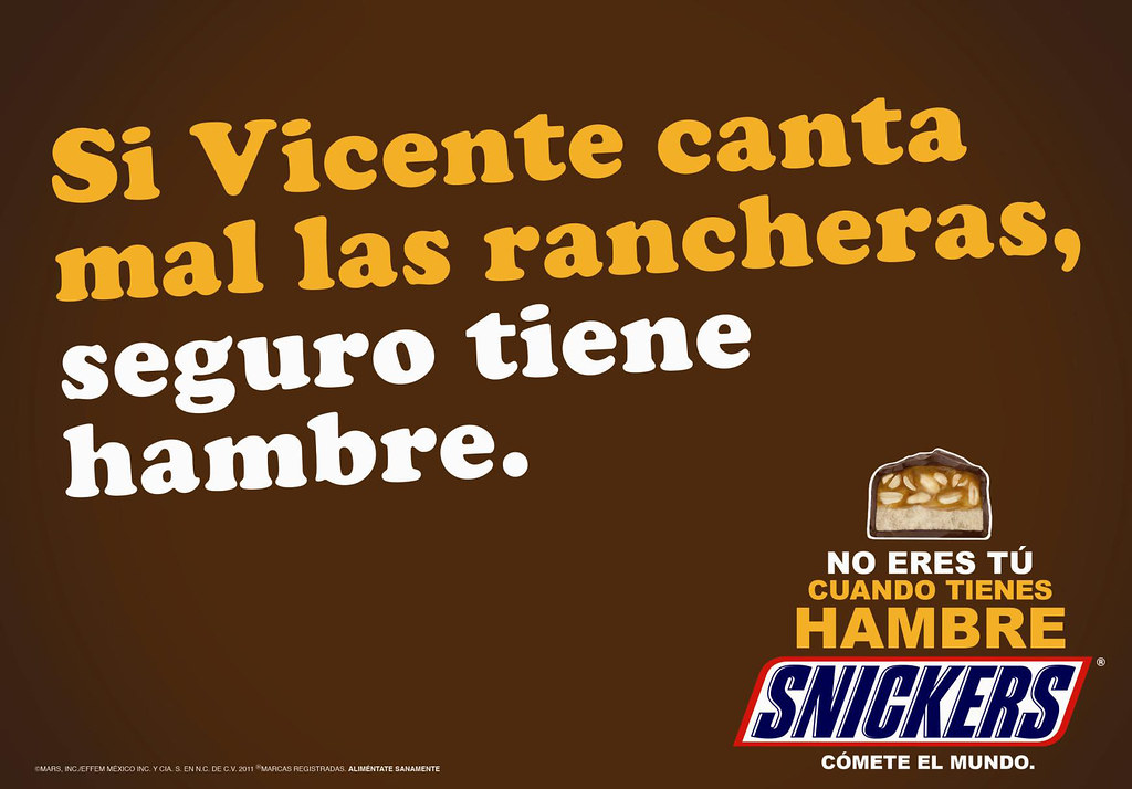 Imagen publicitaria de Snickers que dice: 'Si Vicente canta mal las rancheras, seguro tiene hambre.' En la parte inferior derecha aparece el logotipo de Snickers junto a la frase 'No eres tú cuando tienes hambre' y la imagen de una barra de Snickers partida a la mitad.