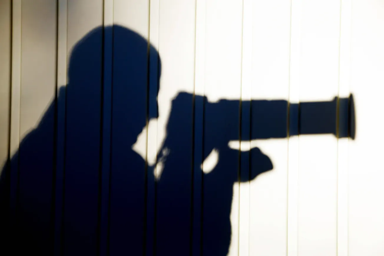 Schatten eines Mannes an einer Wand, der mit einer großen Kamera Menschen beobacht. Credit: IMAGO/Andia