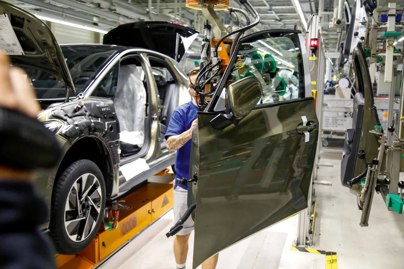 Mitarbeiter montiert in einer Fabrik eine Autotür an einem Auto. Credit: IMAGO/Matthias Wehnert