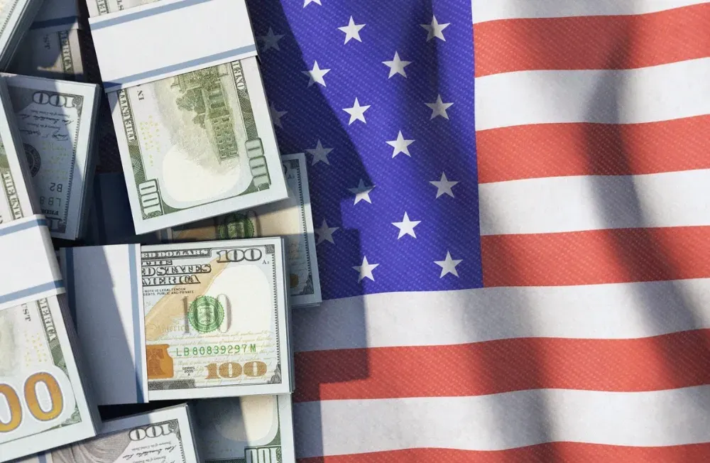 US-Dollar auf US-Flagge (Symbolbild). Credit: IMAGO/IlluPics