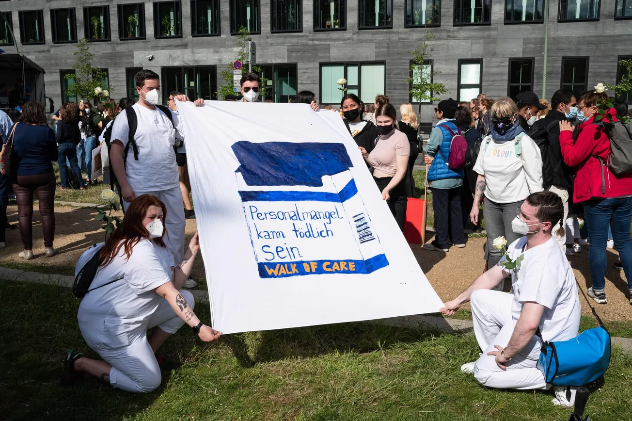 Beschäftigte und Aktivisten im Bündnis »Walk of Care« halten ein Transparent in die Höhe: Personalmangel kann tötlich sein. Credit: IMAGO/Olaf Schuelke.