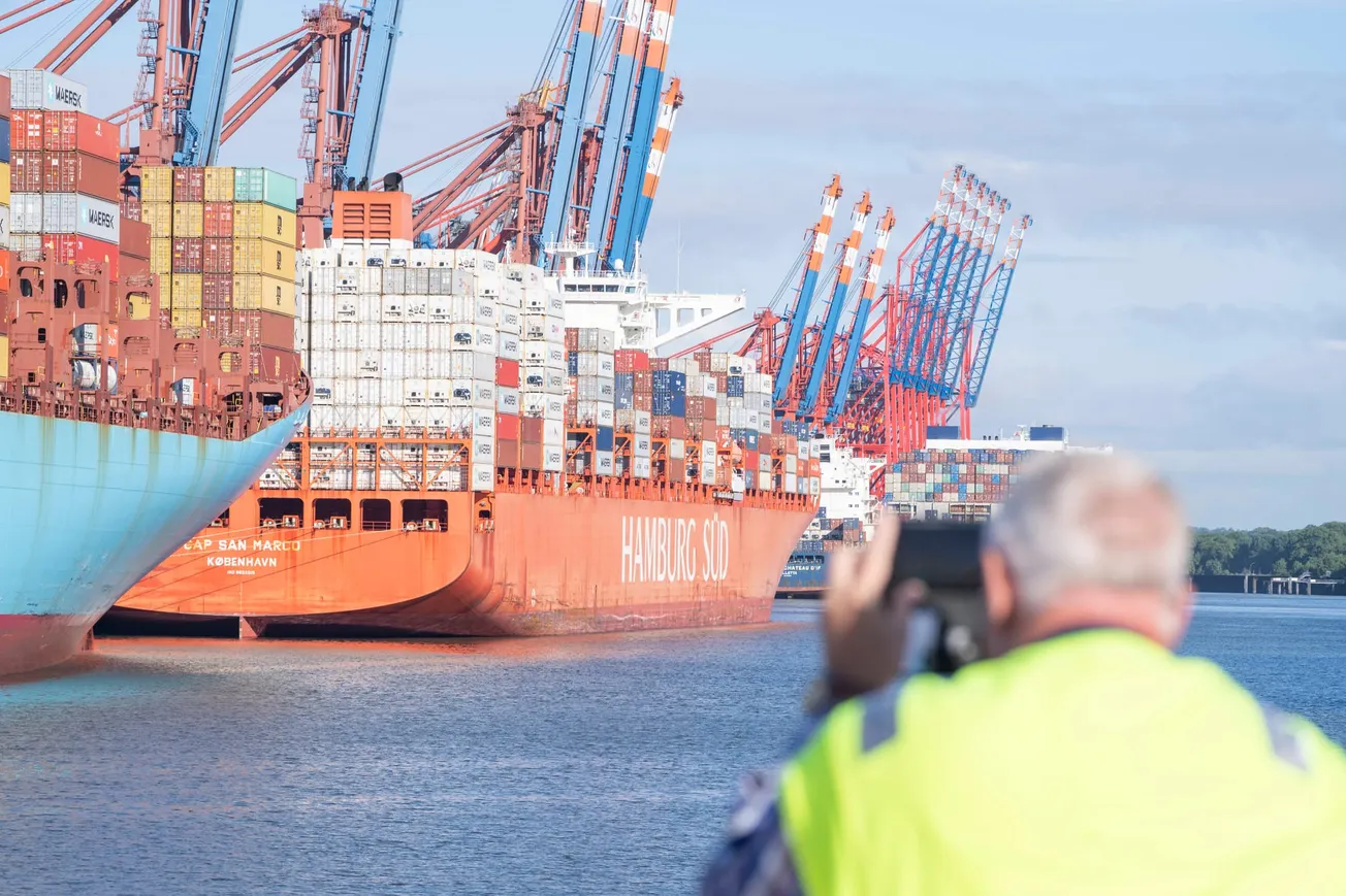 Ein Hafenarbeiter nimmt während eines Streiks im Hamburger Hafen 2022 Aufnahmen von liegenden Containerschiffen (Symbolbild). Credit: IMAGO / Chris Emil Janßen