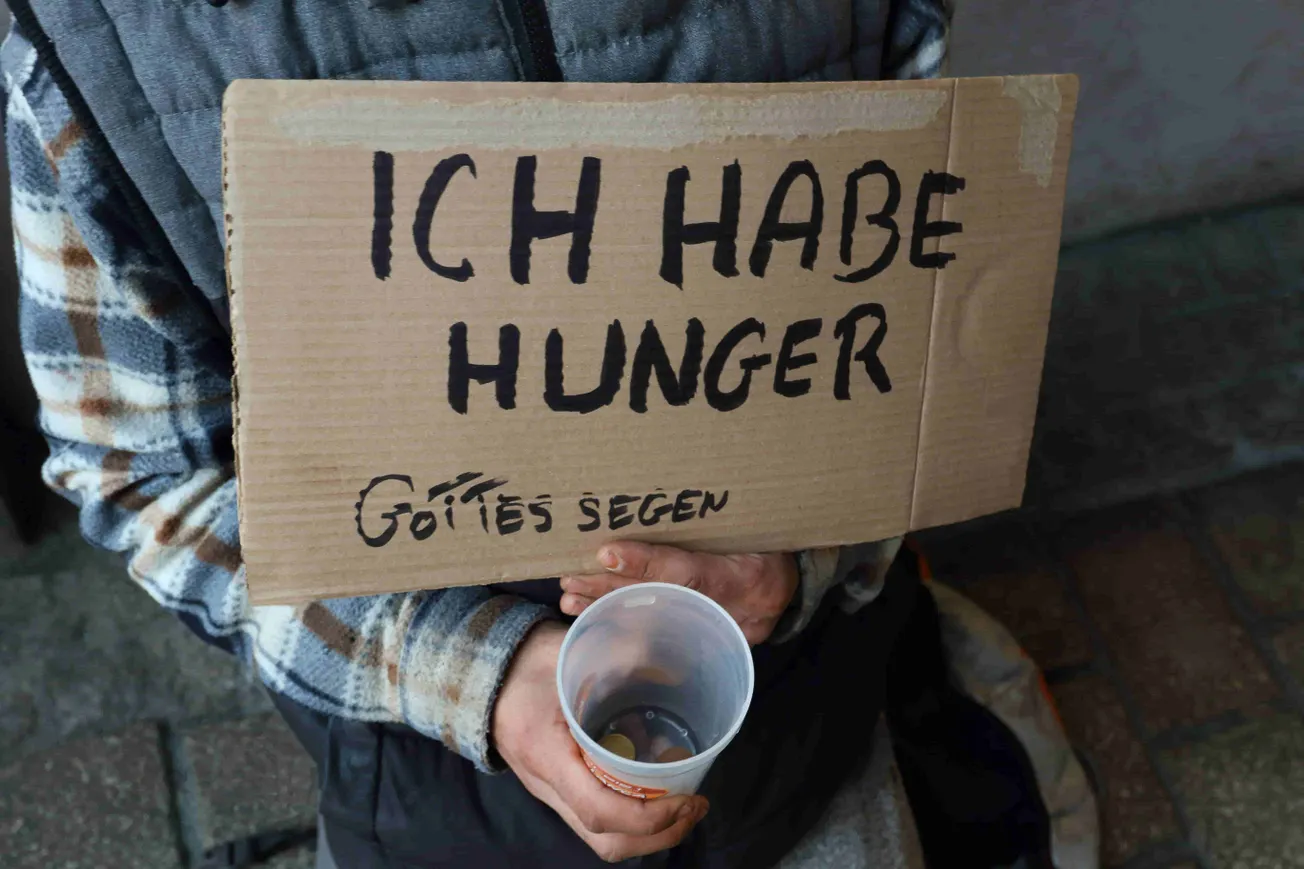 Bettelnde Person mit Pappschild und Becher (Symbolbild). Credit: IMAGO/Müller-Stauffenberg