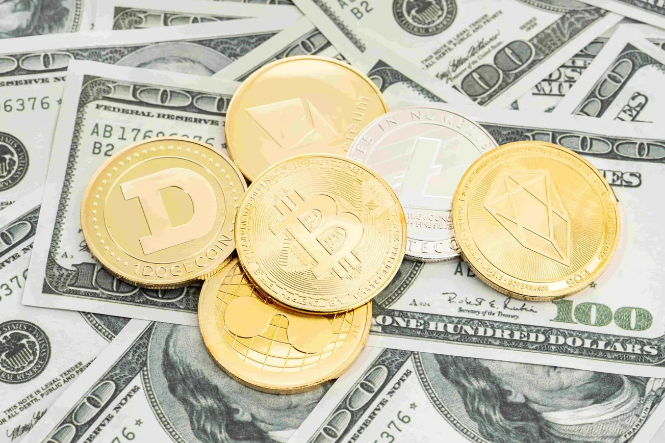 Münzen verschiedener Kryptowährungen auf US-Dollar-Scheinen. Credit: IMAGO/imagebroker