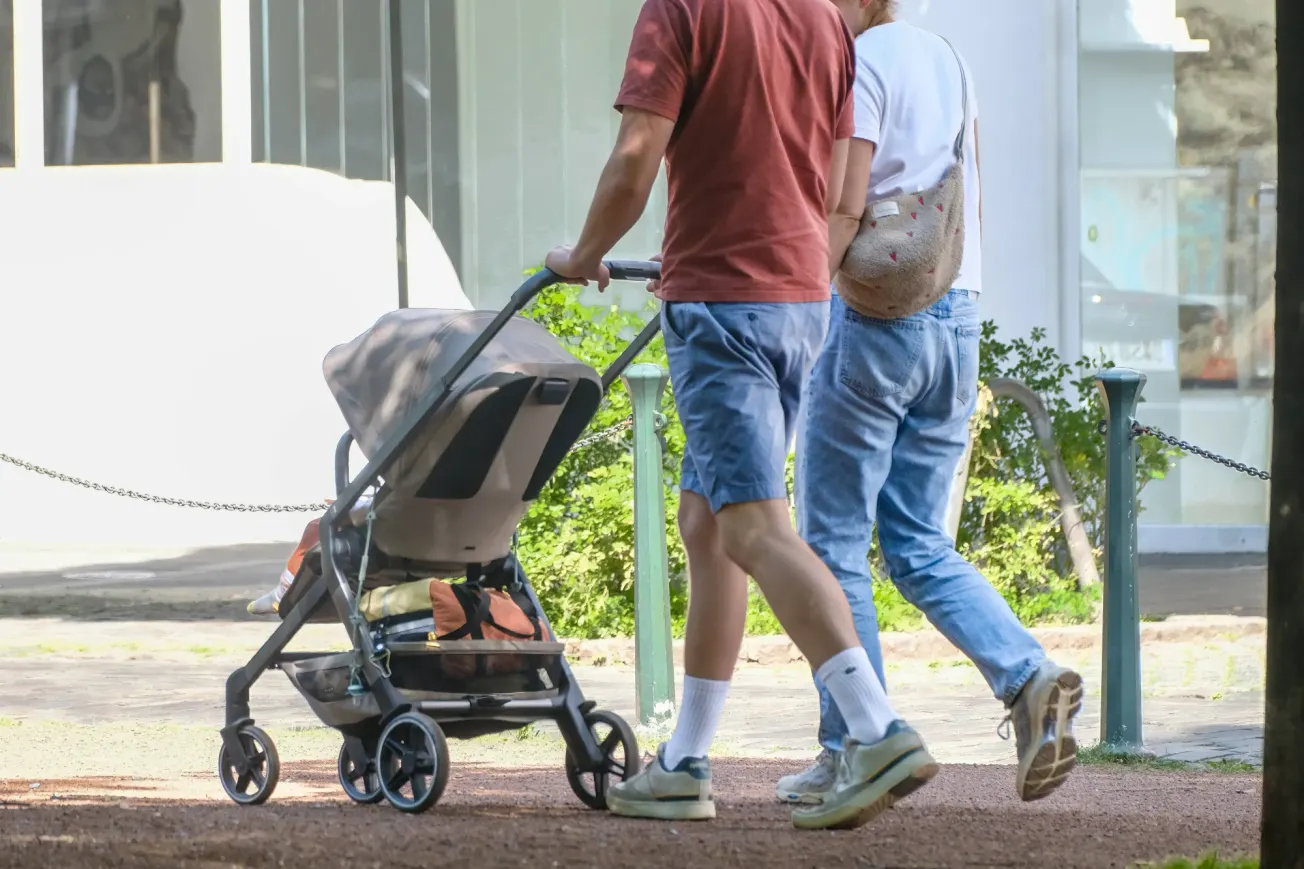 Ein Mann und eine Frau spazieren mit einem Kinderwagen. Credit: IMAGO/Michael Gstettenbauer