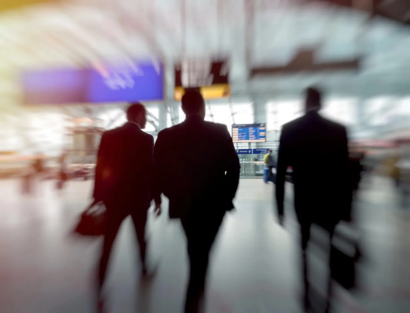 Drei Geschäftsleute laufen durch einen Flughafen. (Symbolbild) Credit: IMAGO/depositphotos