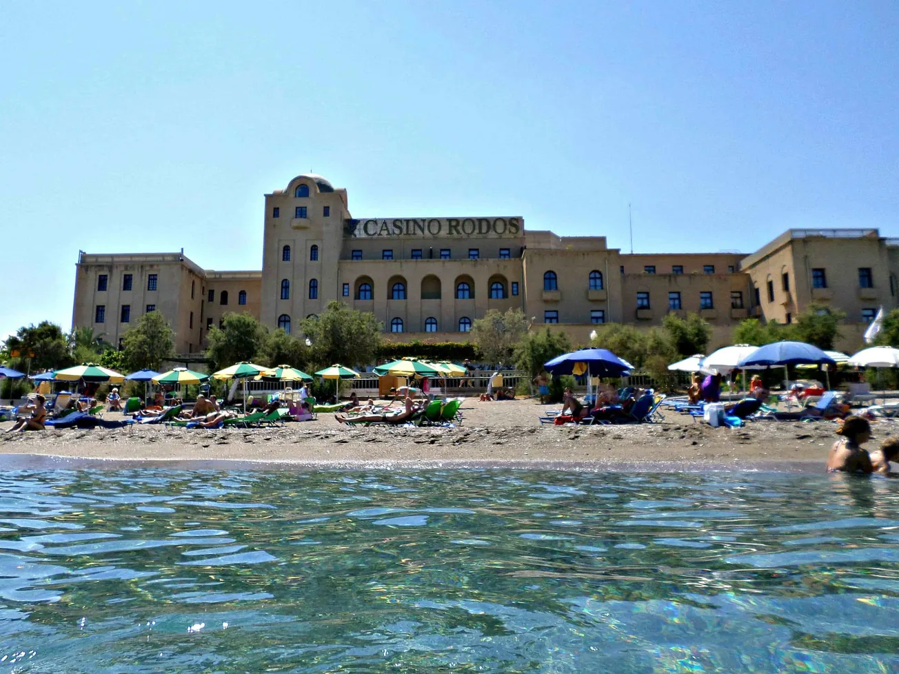 Strand mit Sonnenschirmen vor dem »Casino Rodos« auf Rhodos (Griechenland). Credit: IMAGO/Dreamstime.