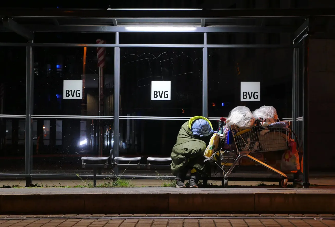 Eine Berliner Tramhaltestelle, an der eine wohnungslose Person in der Kälte verweilt. 