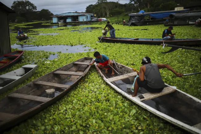 Menschen sitzen auf dem Amazonas-Fluss in Kolumbien auf Fischerbooten (Symbolbild). Credit: IMAGO/Anadolu Agency