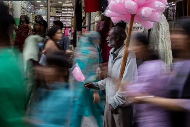 Ein Zuckerwatteverkäufer zwischen Menschen auf einem Markt in Srinagar, Indien. Credit: IMAGO/ZUMA Press Wire