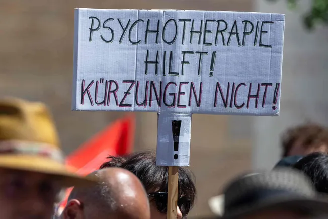 Ein Protestschild mit der Aufschrift »Psychotherapie hilft! Kürzungen nicht!« Credit: IMAGO / Ardan Fuessmann