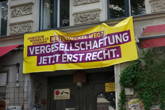 Plakat der Initiative Deutsche Wohnen ung Co enteignen an einer Hausfassade. Credit: IMAGO/Steinach
