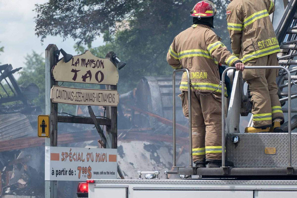 Des pompiers de Saint-Colomban arrosent les débris d'un édifice en démolition sur la rue Labelle, au centre-ville de Saint-Jé