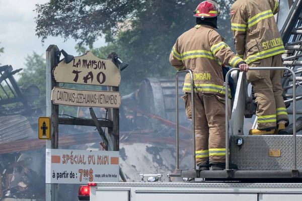 Des pompiers de Saint-Colomban arrosent les débris d'un édifice en démolition sur la rue Labelle, au centre-ville de Saint-Jé