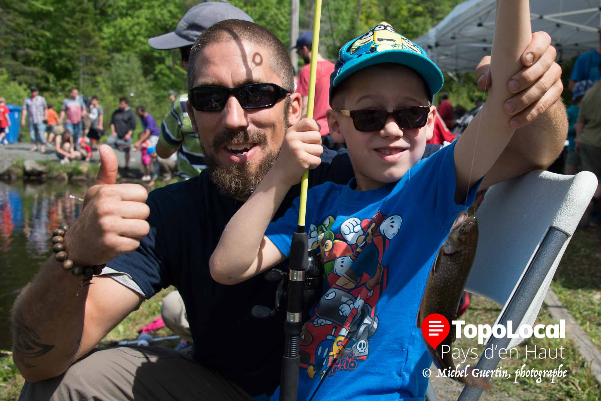 Sourires d'un papa et de son jeune garçon qui vient de prendre sa première truite à vie.