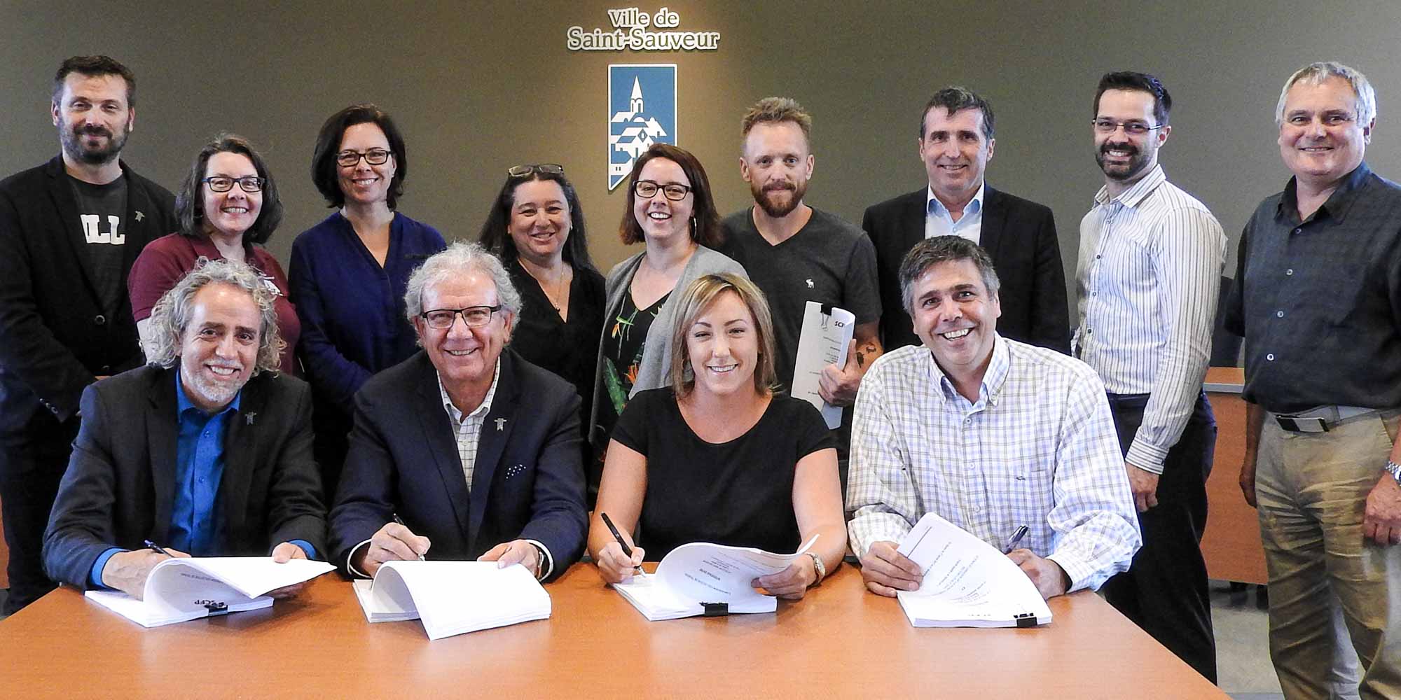À la table: le directeur général Jean Beaulieu, le maire de Saint-Sauveur Jacques Gariépy, Marie-Ève Houle, inspectrice en urbanisme et présidente du syndicat et David Girard, électromécanicien et vice-président du syndicat de la Ville de Saint-Sauveur. Debout: Patrick Gariépy, directeur Service des Travaux publics et du génie, Ginette Gilbert, directrice Service de la vie communautaire, Julie Gratton, conseillère municipale, Rosa Borreggine, conseillère municipale, Ève Pichette Dufresne, technicienne en loisir et membre du comité de négociation, Charles Paquette, journalier-opérateur et membre du comité de négociation, Mario Lamontagne, conseiller Syndicat canadien de la fonction publique, Jean-François Denis, Trésorier et membre du comité de négociation, et Michel Filion, directeur Service des ressources humaines et membre du comité de négociation.