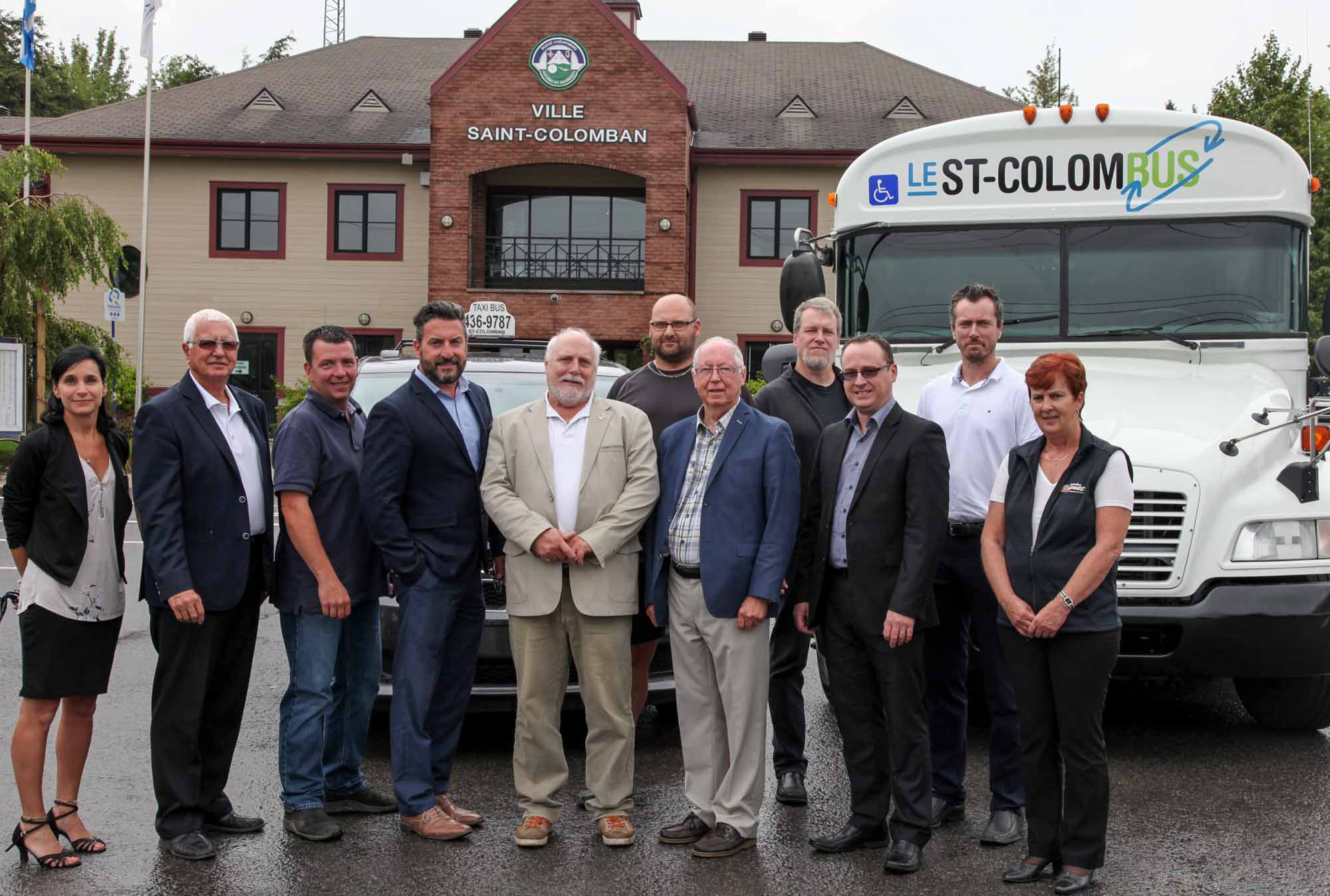 Stéphanie Tremblay, conseillère municipale à Saint-Colomban, Jean-Pierre Brunet, président chez Autobus Brunet, François Boyer, conseiller à Saint-Colomban, Bruno Laroche, préfet de la MRC Rivière-du-Nord et maire de Saint-Hippolyte, Jean Dumais, maire de Saint-Colomban, Jean Desroches, propriétaire d’Allo-Taxi, mandataire du TAC, Germain Richer, président du TAC et maire de Prévost, Steve Gagnon, conseiller à Saint-Colomban, Jonathan Lauzon et Pierre-Alexandre Brunet, respectivement directeur général et vice-président chez Autobus Brunet, et la chauffeuse du St-Colombus, Louise Perreault, lors du lancement du St-Colombus, le 22 août 2017.