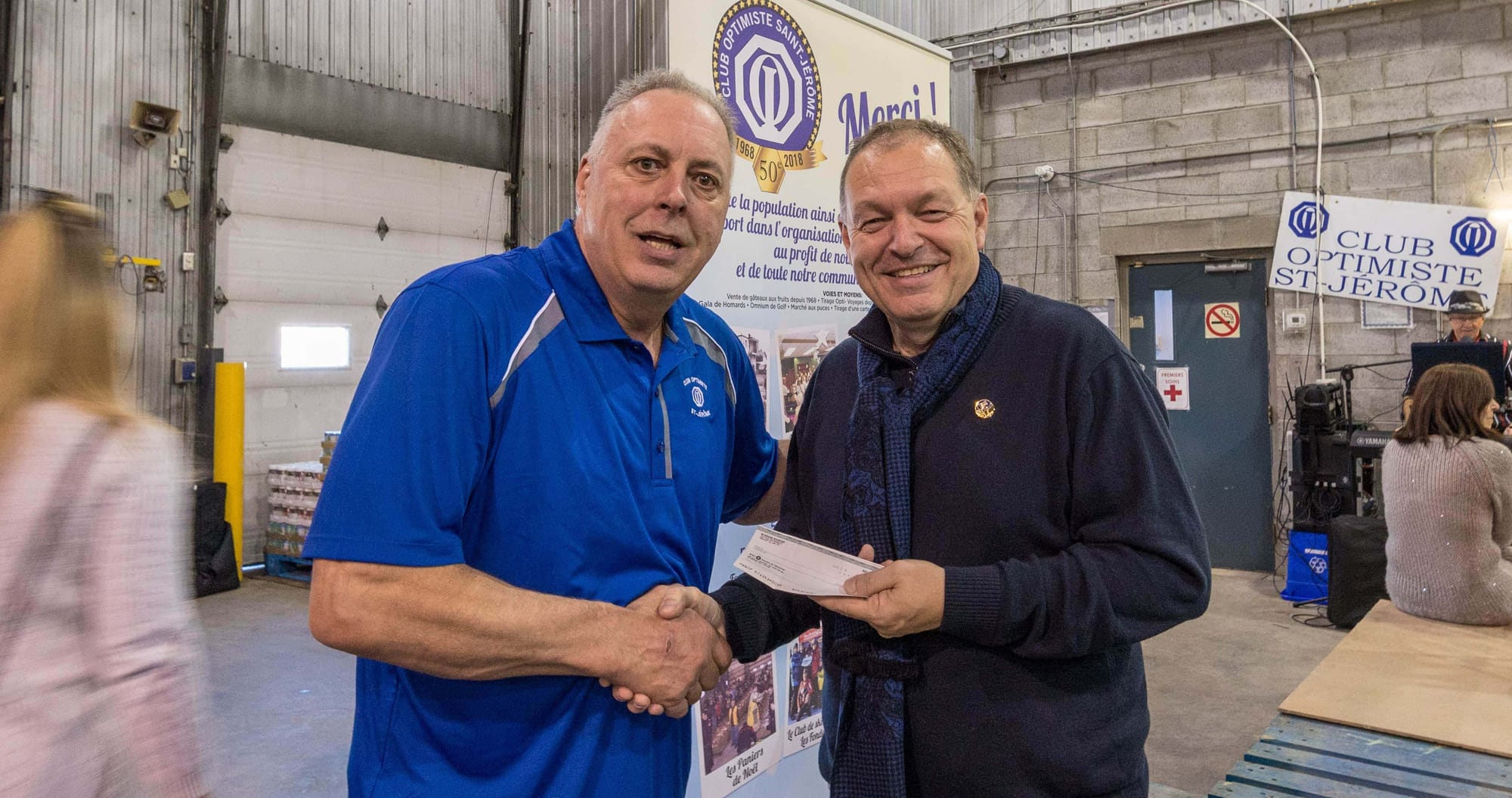 Le président André Allard et le député Marc Bourcier sont tout sourire parce que le chèque qu'ils échangent n'est qu'un accessoire pour la photo. Ce qui est vrai, c'est que le bureau du député remettra au Club optimiste un chèque de 1500$, un vrai celui-là, pour soutenir la campagne des paniers de Noël...