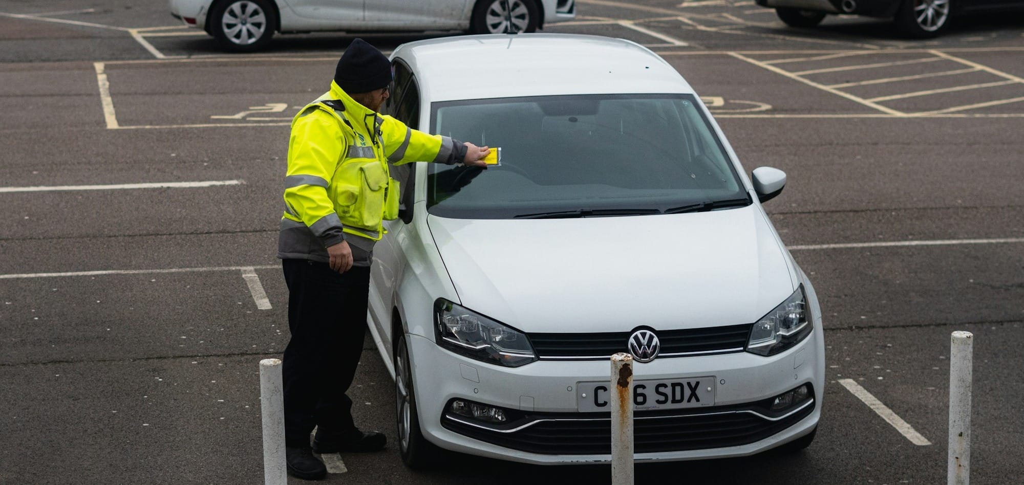 man in yellow jacket standing beside white car