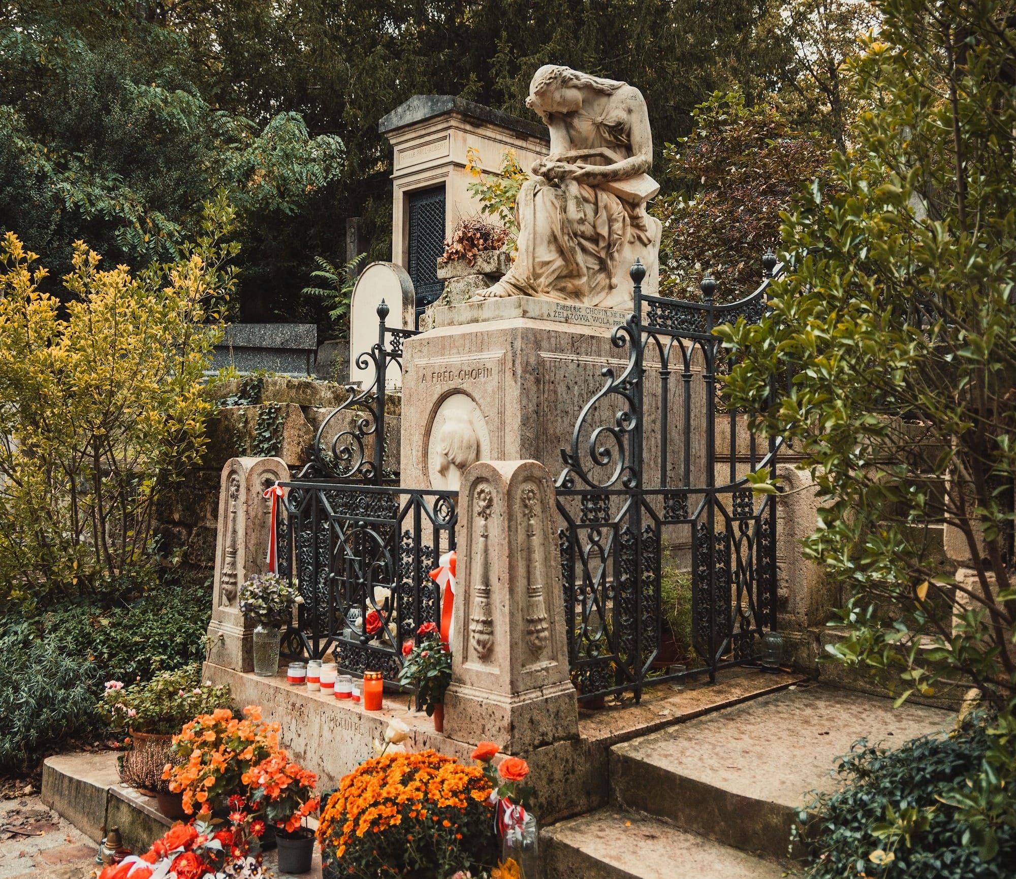 a cemetery with a statue and flowers in the foreground
