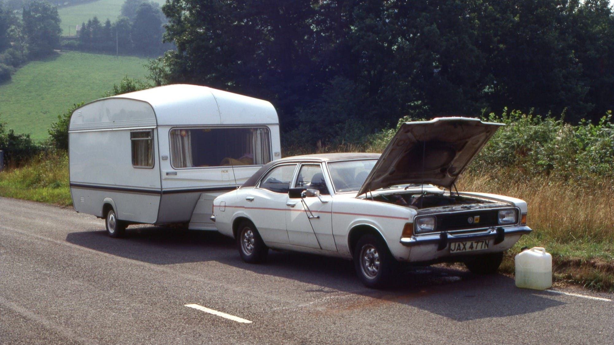 a car with a camper on the back of it parked next to a truck