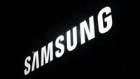 The image features the illuminated logo of Samsung, prominently displayed against a dark background. The logo is captured in a way that emphasizes its modern and sleek design.