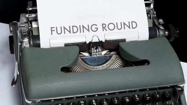 An antique typewriter with a sheet of paper emerging from it that reads 'FUNDING ROUND.' The image highlights the connection between traditional writing tools and modern financial concepts.